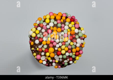 Macro image of a 'freckle', chocolate bud coated in sprinkles, isolated on a grey background Stock Photo