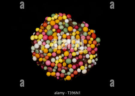 Macro image of a 'freckle', chocolate bud coated in sprinkles, isolated on a black background Stock Photo