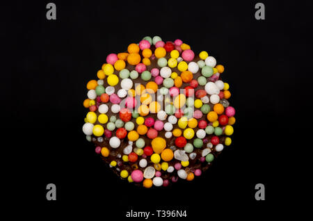 Macro image of a 'freckle', chocolate bud coated in sprinkles, isolated on a black background Stock Photo