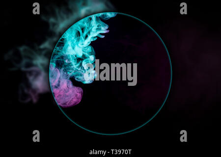Close-up colorful pink and blue smoke   blown under a magnifying glass  on a black isolated background. Background from the smoke of vape Stock Photo