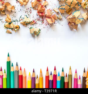 Row of colored sharpened crayons and colored shavings on paper background Stock Photo