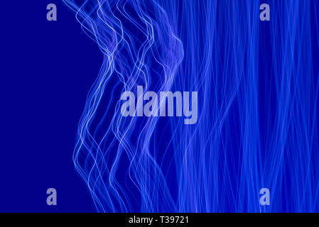 Blue light painting photography, long exposure waves and curves against a blue background Stock Photo