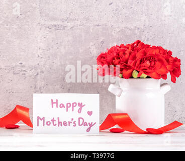 May mothers day handmade giftbox wishes design photography - Beautiful blooming carnations in vase isolated on gray, wooden background table, close up Stock Photo