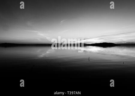 erfectly symmetrical, beautiful view of Trasimeno lake (Umbria, Italy) at sunset, with cloud shapes on the sky Stock Photo
