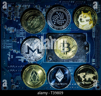 Top view of Bitcoin,Ripple,Ethereum,Eos,Monero,Iota,Dogecoin cryptocurrency physical coins on computer mother board processor.Bitcoin mining farm, wor Stock Photo