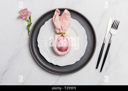 Rabbit easter egg in napkin on plate. Table setting for Easter meal. Stock Photo