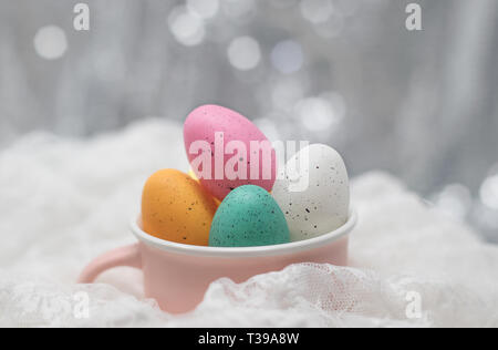 Easter eggs in a pink cup, on white lace with a soft bokeh background Stock Photo