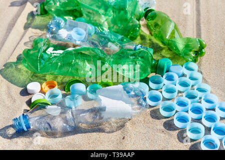 Close up picture of used plastic bottles and caps on a beach, selective focus. Stock Photo