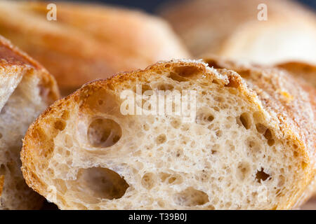Cut into pieces a loaf of bread with holes, gray bread is a long baguette Stock Photo