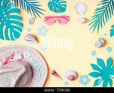 Summer background. Beach accessories with  shells and tropical leaves on light yellow background, top view. Straw hat and sunglasses. Summer holiday v Stock Photo