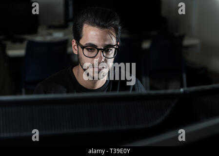 View over a screen of the face of a young computer science student working with the computer. Stock Photo
