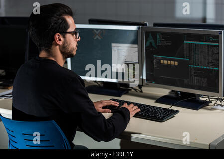 Young computer science student developing with his computer on a Linux System over double screen system Stock Photo