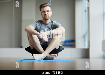 Serious young man waiting for yoga class Stock Photo