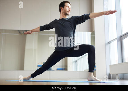Slim man doing standing yoga pose Stock Photo