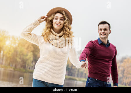 Enjoying day together. Portrait beautiful young couple in casual wear holding hands together and smiling while walking outdoors. Young couple in love. Stock Photo