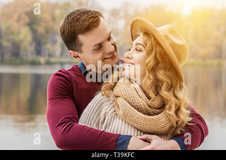 Romantic couple. Cropped image of beautiful hugging couple looking at each other and smiling while standing outdoors. Handsome man embracing his attra Stock Photo