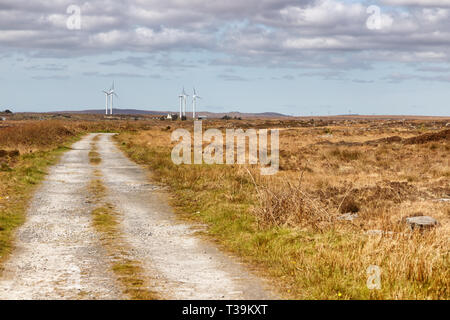 Farm road in a bog with wind power and typical vegetation and rocks, Spiddal, Galway, Ireland Stock Photo