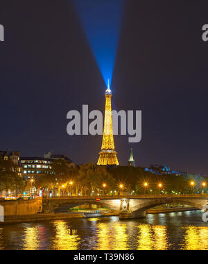 PARIS, FRANCE - NOVEMBER 10, 2018: Siene river embankment and Eiffel Tower with spotlight at night in Paris. Stock Photo