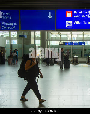 FRANKFURT AM MAIN, GERMANY - AUGUST 29, 2018: People with luggage exiting Frankfurt airport, Info board with direction signs above, Frankfurt am Main, Stock Photo