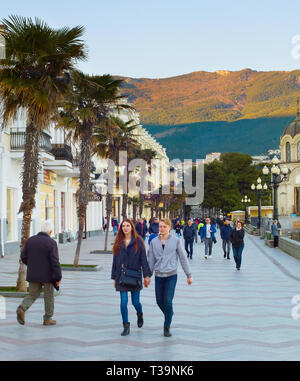 YALTA, CRIMEA, UKRAINE - APRIL 03, 2018: Couple walking by Yalta promenade at sunset. Yalta is the most famous tourist destination in Crimea Stock Photo