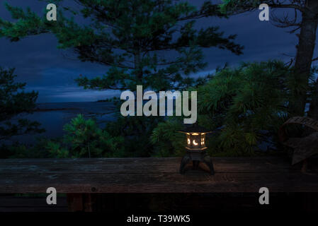 Candle-lit lantern on bench overlooking the Georgian Bay in Ontario, Canada, at dusk. Stock Photo