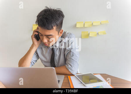 Asian office man talking on phone with customer Stock Photo