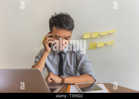 Young businessman looking at watch and talking on phone Stock Photo