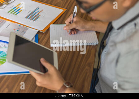 Young man using tablet and writing note Stock Photo