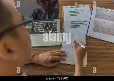 Rear view of man writing into note Stock Photo