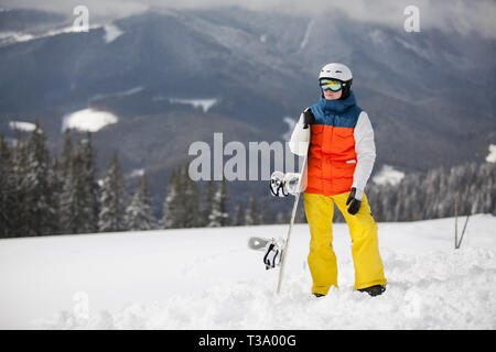 female snowboarder against sun and blue sky. Beautiful mountain landscape in the background. Photo on a theme of extreme sports, winter sports, snowbo Stock Photo