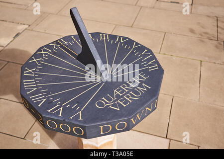 A horizontal bronze sundial with the Latin inscription 'Quaerere Verum' ('Search for the truth' in English) on a stone pedestal. Landscape format. Stock Photo