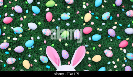 Bright and colorful Easter eggs and candy with pink bunny ears Stock Photo