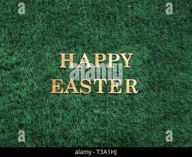 Happy Easter gold text laying in green grass Stock Photo