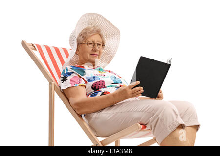 Senior woman sitting in a deck chair and reading a book isolated on white background Stock Photo