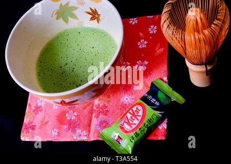 A Japanese Uji Matcha green tea Kit Kat sits next to a bowl of brewed thin tea. Stock Photo
