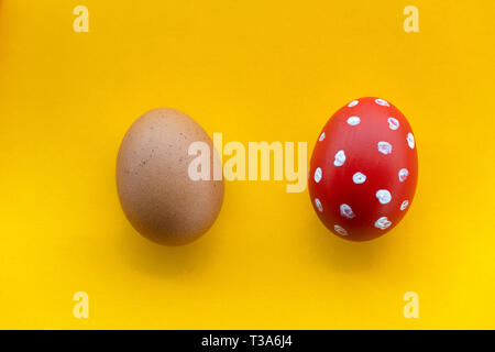 two Easter holiday eggs white polka dot with red painted and raw one for decoration on colorful yellow background Stock Photo