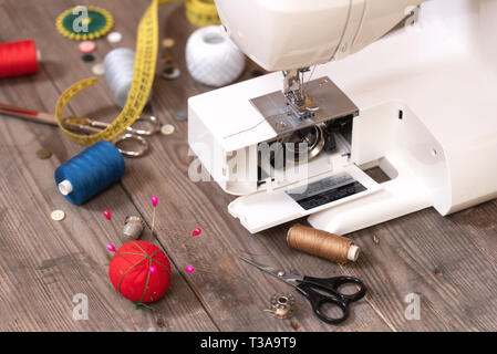 Seamstress or tailor background with sewing tools, colorful threads, sewing machine and accesories. Stock Photo