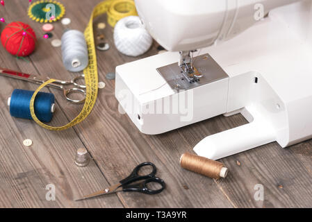 Seamstress or tailor background with sewing tools, colorful threads, sewing machine and accesories. Stock Photo
