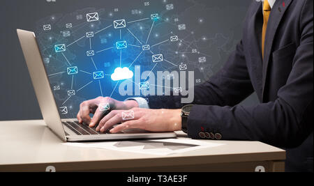 Businessman hand sending a bunch of messages on laptop with cloud Businessman hand sending a bunch of messages on laptop with cloud