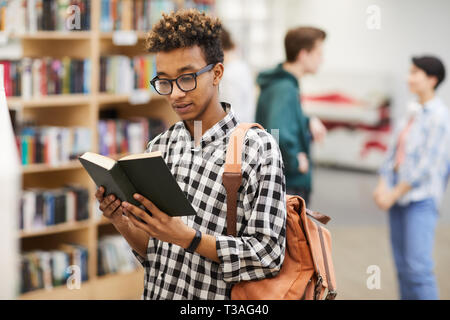 Intelligent guy reading book in library Stock Photo