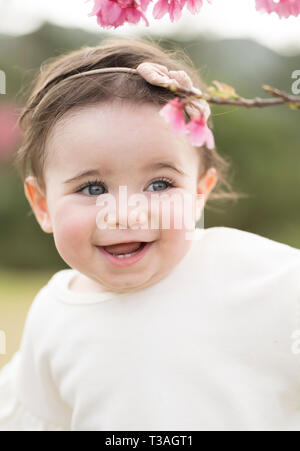 1- year-old toddler outside with cherry blossom flowers Stock Photo