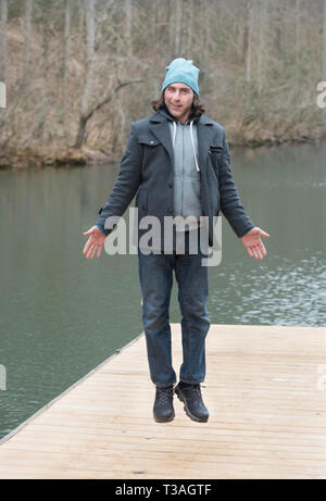 Man floating over dock on lake, a jump calculated to look like a man floating up gently Stock Photo