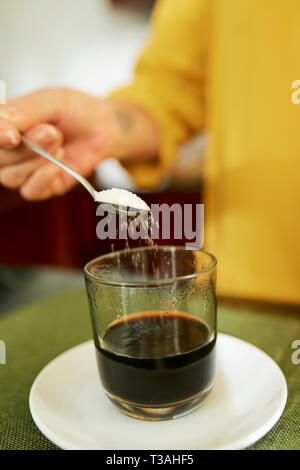 Woman adding sweetener in coffee Stock Photo