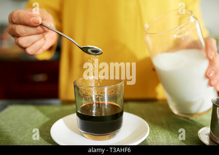 Woman adding sugar in her espresso Stock Photo