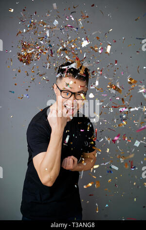 Young man under falling confetti Stock Photo
