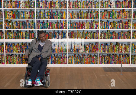 London, UK. 8th April, 2019. Artist, Yinka Shonibare CBE, at Tate Modern alongside his installation The British Library, the latest artwork to be acquired by Tate.The British Library is a site-specific installation with a digital platform for visitors to join in the discussion. A celebration of the diversity of the British population it contains 6,328 books bound in ‘Dutch wax print’, a fabric characteristically used by the artist in his work. Credit: Malcolm Park/Alamy Live News. Stock Photo