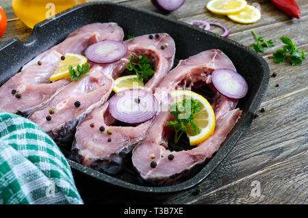 Raw steaks river fish on the grill pan on a wooden table. Carp ready for cooking. Stock Photo