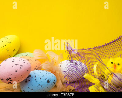 easter eggs and yellow chickens in a nest isolated on yellow background, postcard Stock Photo