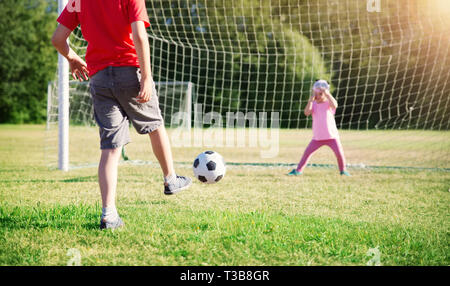 Boys playing football on the field with gates Stock Photo