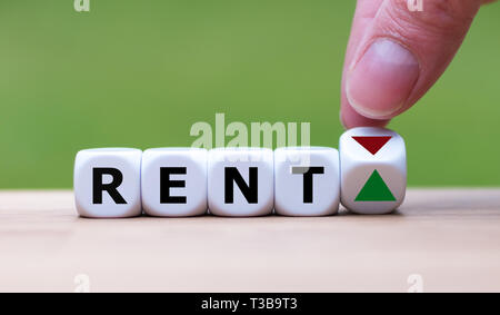 Symbol for increasing rent. Hand is turning a dice and changes the direction of an arrow symbolizing that rents are going up (or vice versa). Stock Photo